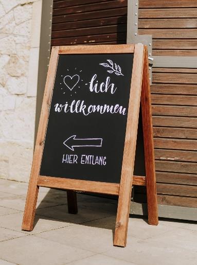 Wiederverwendbares
Willkommensschild aus
Holz mit
handgeschriebener
Kreide-Aufschrift für eine
umweltfreundliche
Hochzeit.